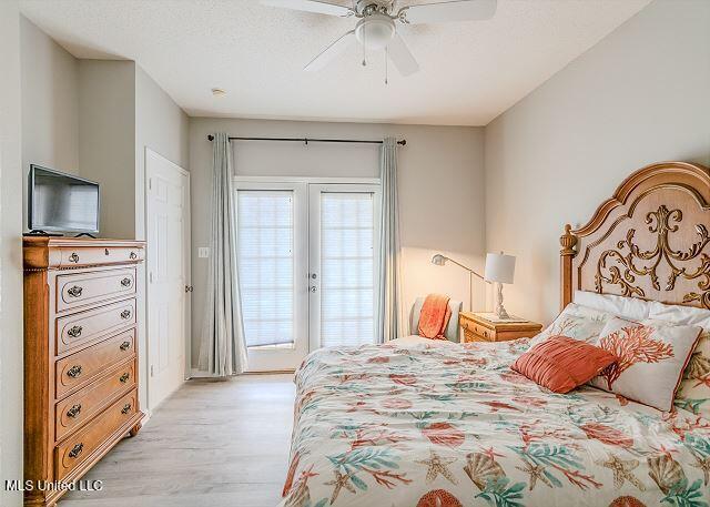 bedroom featuring ceiling fan, light hardwood / wood-style floors, a textured ceiling, and access to outside