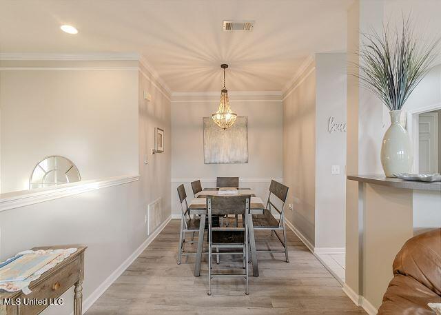 dining room featuring light hardwood / wood-style flooring, ornamental molding, and a notable chandelier