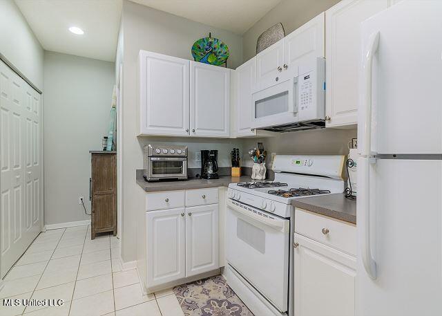 kitchen featuring white cabinets, light tile patterned flooring, and white appliances