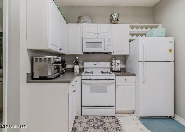 kitchen featuring white cabinetry, white appliances, and light tile patterned floors