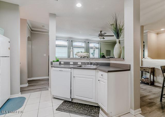 kitchen featuring ceiling fan, sink, white appliances, white cabinets, and ornamental molding