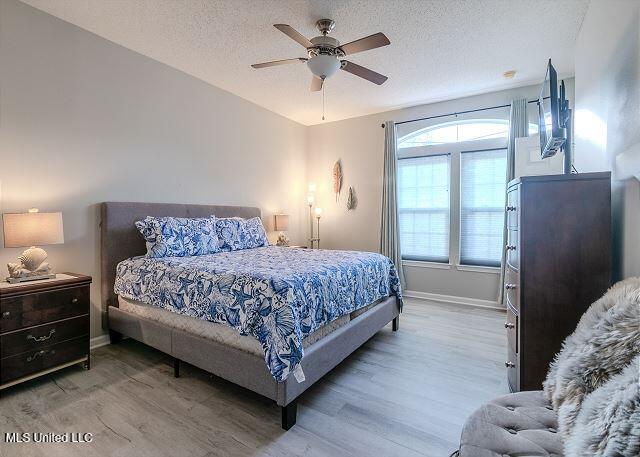 bedroom featuring a textured ceiling, hardwood / wood-style flooring, and ceiling fan