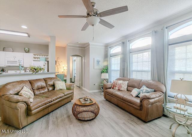 living room featuring ceiling fan, light hardwood / wood-style floors, and ornamental molding