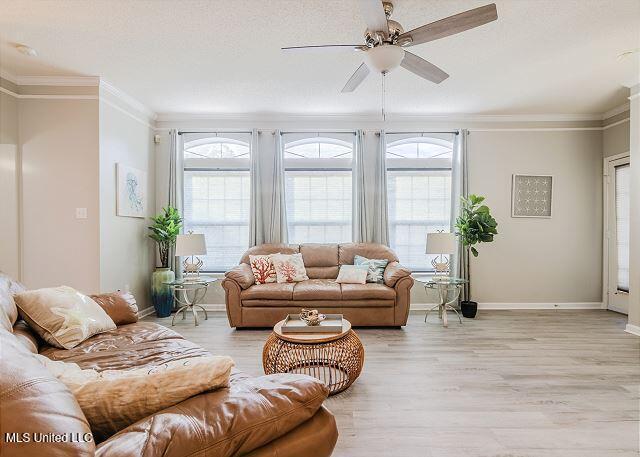 living room with plenty of natural light, ceiling fan, light hardwood / wood-style floors, and ornamental molding