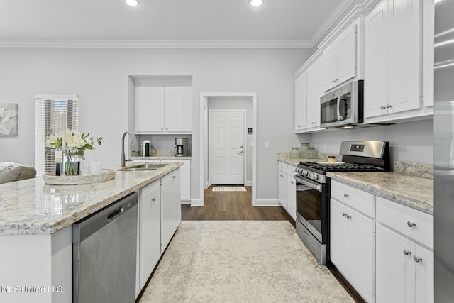 kitchen with a sink, stainless steel appliances, crown molding, and white cabinetry