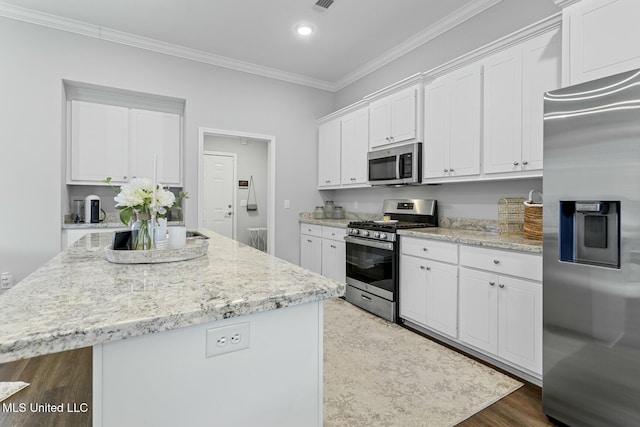 kitchen with white cabinets, ornamental molding, wood finished floors, and stainless steel appliances