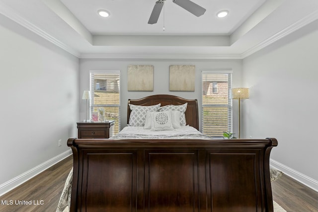 bedroom with dark wood finished floors, a tray ceiling, and baseboards