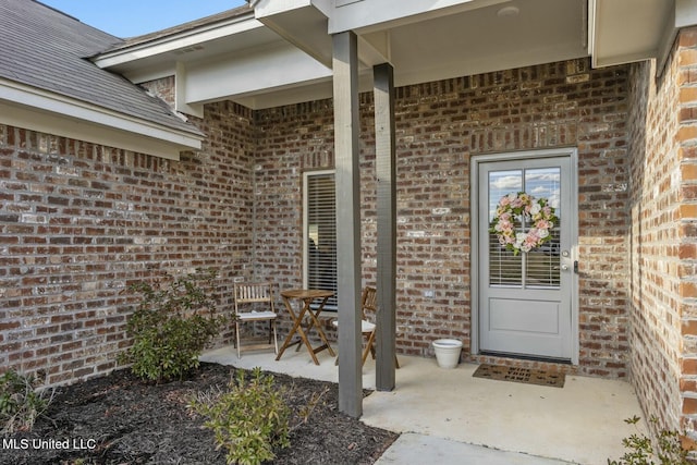 property entrance featuring a patio area and brick siding