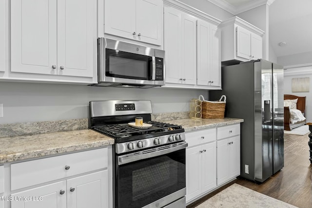 kitchen with white cabinets, light stone countertops, stainless steel appliances, and dark wood-style flooring