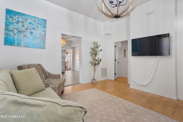 living room featuring a notable chandelier, a towering ceiling, and hardwood / wood-style floors