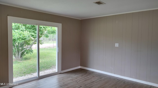 spare room featuring wood finished floors, crown molding, and baseboards