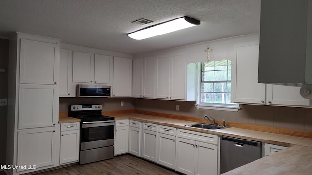 kitchen featuring stainless steel appliances, a sink, light countertops, and a textured ceiling