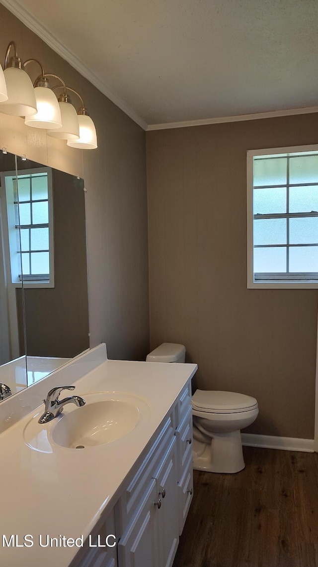 bathroom featuring wood finished floors, toilet, vanity, healthy amount of natural light, and ornamental molding