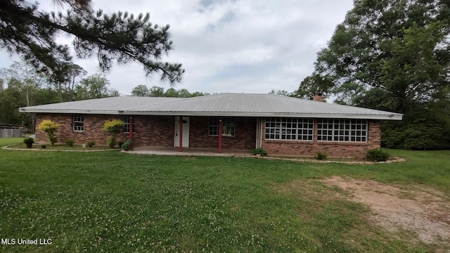 single story home with a front yard, brick siding, a chimney, and metal roof