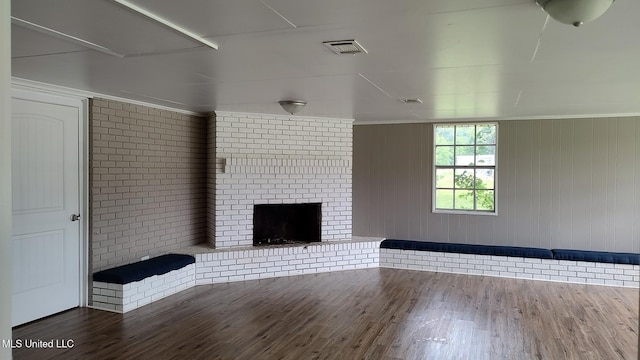 unfurnished living room with a brick fireplace and wood finished floors