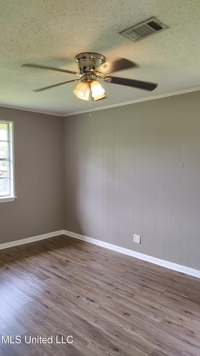 spare room with wood finished floors, ceiling fan, baseboards, a textured ceiling, and ornamental molding