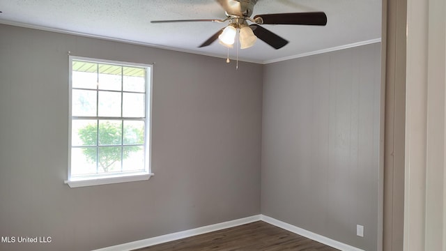 spare room featuring healthy amount of natural light, dark wood-type flooring, ornamental molding, ceiling fan, and baseboards
