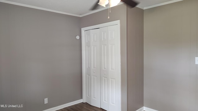 unfurnished bedroom featuring a closet, dark wood-style floors, baseboards, crown molding, and a ceiling fan