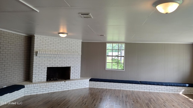 unfurnished living room with wood finished floors and a brick fireplace
