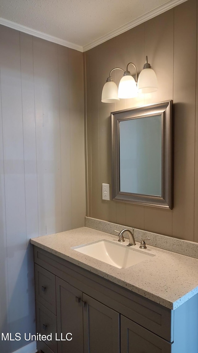 bathroom with ornamental molding, vanity, and a decorative wall