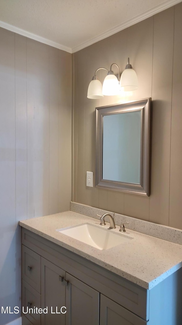 bathroom with crown molding, vanity, and a decorative wall