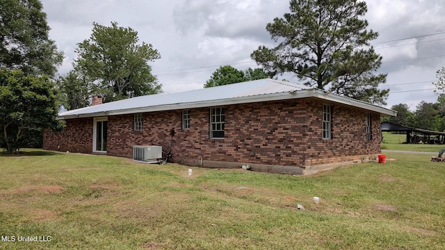 view of property exterior with a lawn, central AC unit, and brick siding