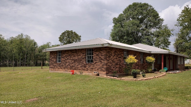 view of home's exterior with a yard, metal roof, and brick siding