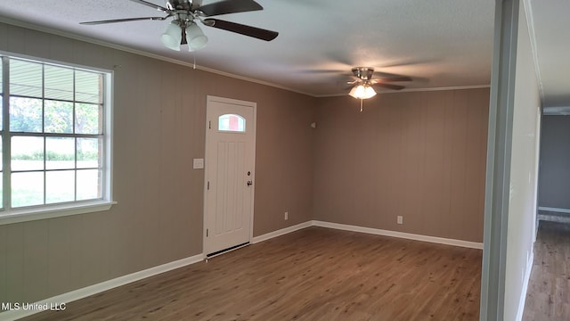 foyer featuring wood finished floors, ceiling fan, healthy amount of natural light, ornamental molding, and baseboards