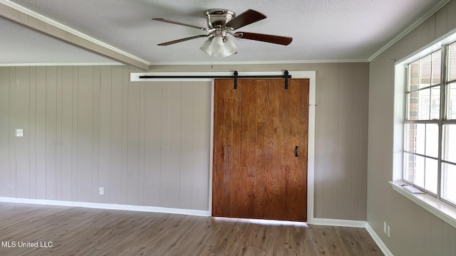 spare room featuring wood finished floors, baseboards, plenty of natural light, ceiling fan, and crown molding