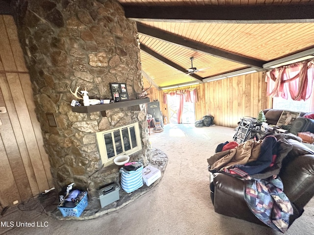 carpeted living room featuring wood ceiling, a stone fireplace, lofted ceiling with beams, and wood walls