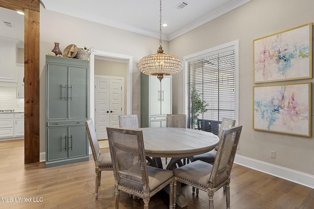 dining space featuring visible vents, a notable chandelier, crown molding, light wood finished floors, and baseboards