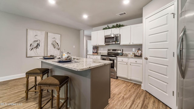 9624 Reserve Blvd, Biloxi, MS 39532 - kitchen featuring stainless steel appliances, a breakfast bar, light wood-style floors, white cabinetry, and recessed lighting