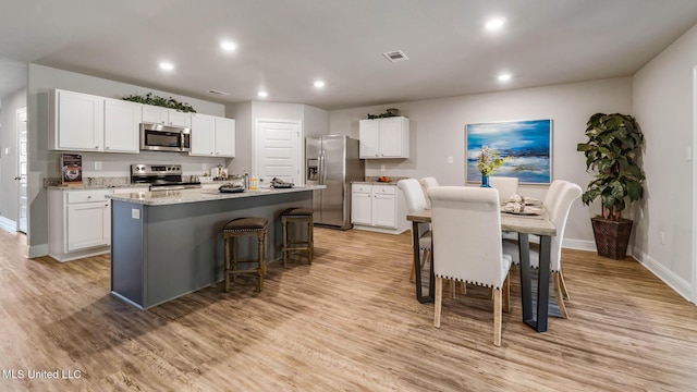 9624 Reserve Blvd, Biloxi, MS 39532 - kitchen with stainless steel appliances, baseboards, a kitchen island with sink, white cabinets, and recessed lighting