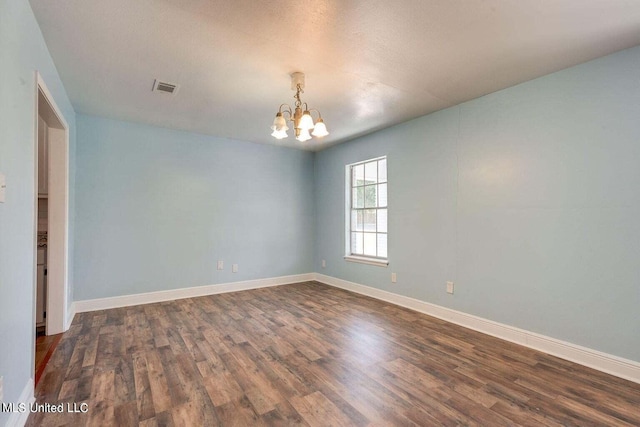 spare room with a textured ceiling, a notable chandelier, and dark hardwood / wood-style floors