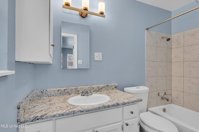 full bathroom featuring vanity, tiled shower / bath, and toilet