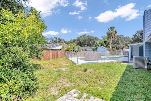 view of yard featuring central air condition unit and a fenced in pool