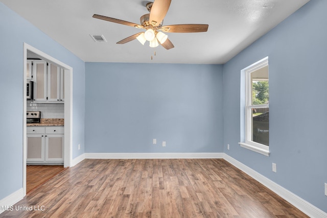 spare room with ceiling fan and light wood-type flooring