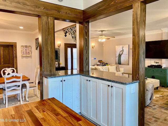 kitchen with ornamental molding, white cabinets, dark stone counters, and ceiling fan