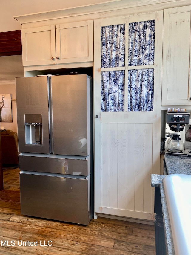 kitchen with white cabinetry, stainless steel refrigerator with ice dispenser, wood-type flooring, and dark stone counters