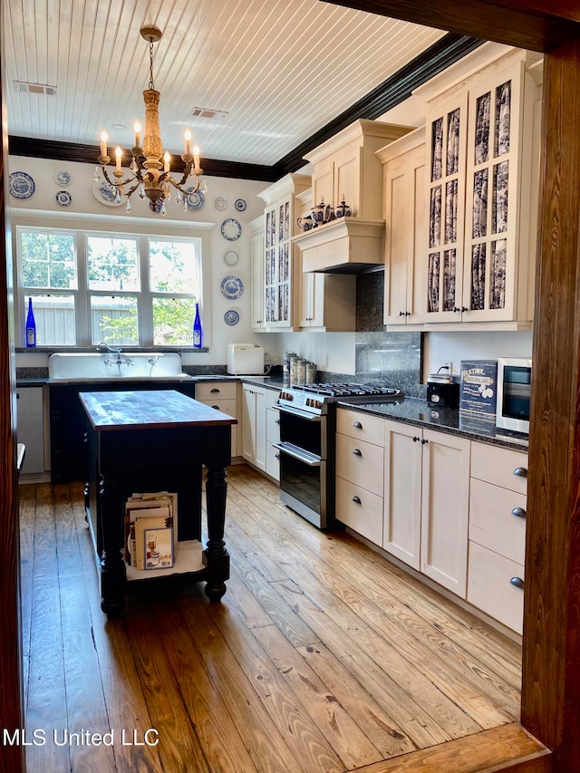 kitchen with appliances with stainless steel finishes, an inviting chandelier, light hardwood / wood-style flooring, ornamental molding, and pendant lighting