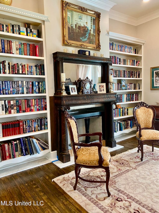 sitting room with crown molding, hardwood / wood-style flooring, and built in features