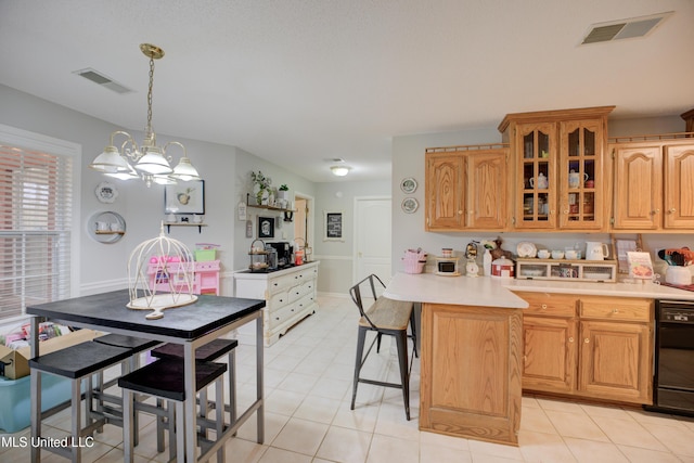 kitchen with light countertops, glass insert cabinets, visible vents, and a kitchen breakfast bar