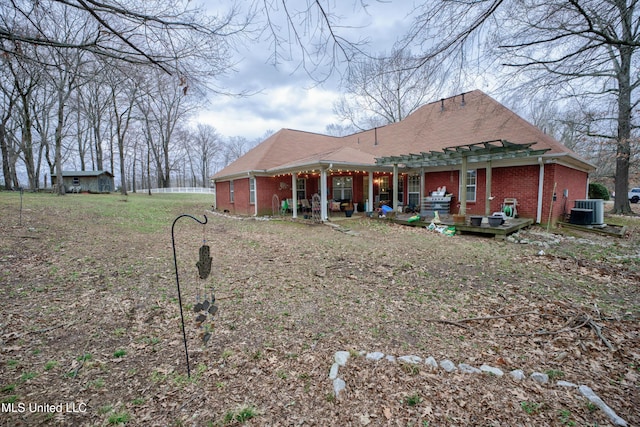 back of house featuring brick siding, central AC unit, and a pergola