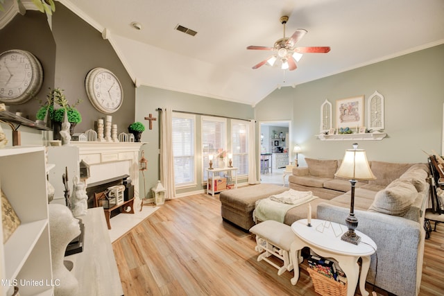 living room featuring crown molding, lofted ceiling, visible vents, a fireplace with flush hearth, and wood finished floors