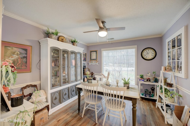 dining room with visible vents, ceiling fan, ornamental molding, wood finished floors, and a textured ceiling