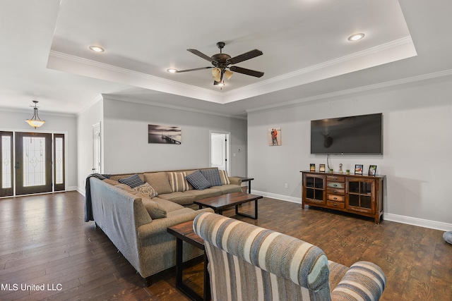 living room with ceiling fan, ornamental molding, a tray ceiling, and dark hardwood / wood-style floors