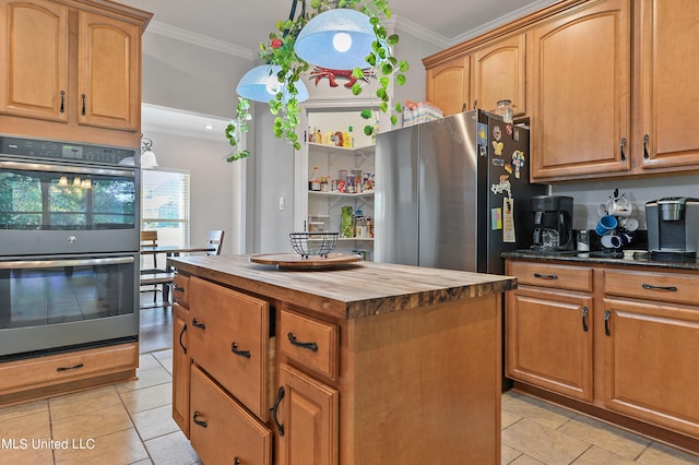 kitchen with appliances with stainless steel finishes, light tile patterned flooring, wooden counters, and a center island