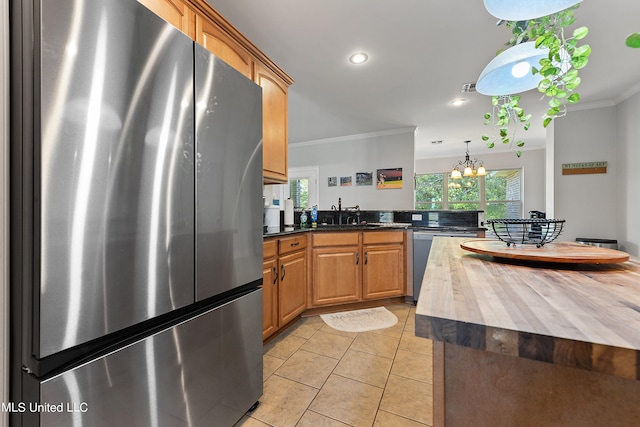 kitchen featuring crown molding, wood counters, appliances with stainless steel finishes, and plenty of natural light