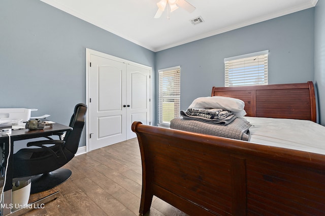 bedroom with ceiling fan, hardwood / wood-style flooring, multiple windows, and crown molding