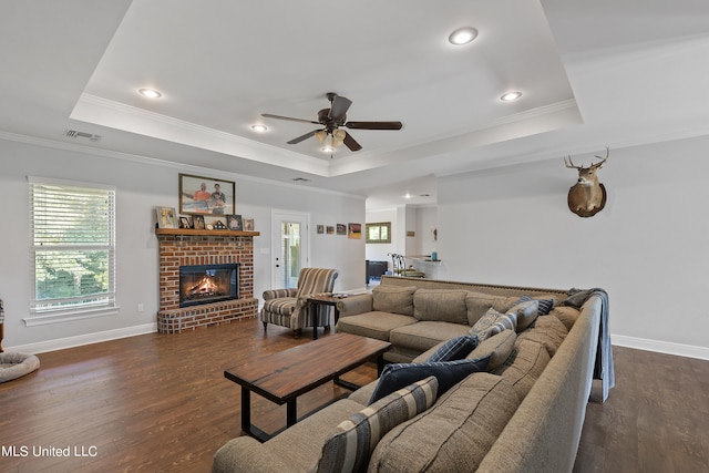 living room with ornamental molding, a tray ceiling, and dark hardwood / wood-style flooring